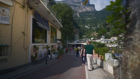 Amalfi-Positano-Italia-Viajes-De-Inmersión-Turismo-Mar-Mediterráneo-Costa-Agua-Europa,-Caminar,-4k-|-Turistas-Caminando-Explorando-El-Mercado-En-Caminos-Debajo-De-Famosas-Casas-En-La-Ladera-De-La-Montaña,-Temblorosos