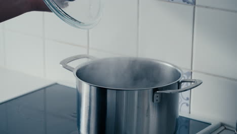 Close-up-of-woman's-hand-opening-the-Lid-on-a-big-Iron-Pot-with-boiling-and-steaming-Water-bubbling-on-the-stove-in-the-kitchen-in-slow-motion
