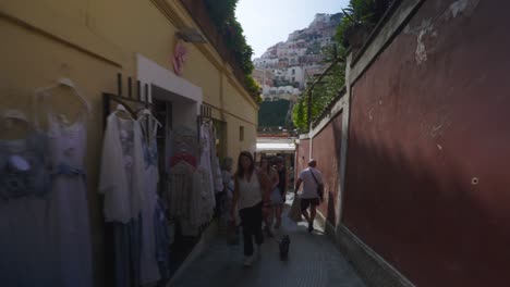 Amalfi-Positano-Italy-Immersive-Travel-Tourism-Mediterranean-Sea-Coast-Water-Europe,-Walking,-4K-|-Turning-a-Corner-in-a-Crowded-Alley-in-Shadows-to-Reveal-Bright-Scenic-Mountainside-Homes-on-Cliff