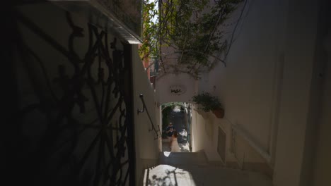 Amalfi-Positano-Italy-Immersive-Travel-Tourism-Mediterranean-Sea-Coast-Water-Europe,-Walking,-4K-|-Dark-Crowded-Alley-Passing-Couple-Exploring-Roads-Below-Famous-Mountainside-Cliffs,-Shaky