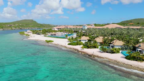 Private-Caribbean-villas-with-inifinity-pools-line-shoreline-with-larger-resort-pool-at-center,-Curacao