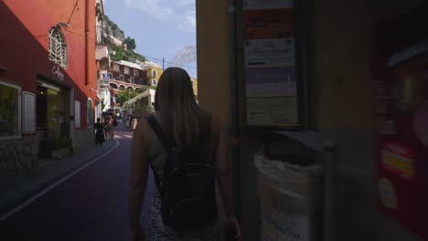 Amalfi-Positano-Italy-Immersive-Travel-Tourism-Mediterranean-Sea-Coast-Water-Europe,-Walking,-4K-|-Moving-Behind-Female-Backpackers-Exploring-Roads-Below-Famous-Mountainside-Cliffs,-Shaky