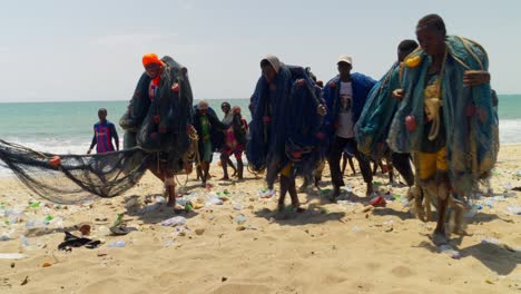 Pueblo-Africano-Llevando-Redes-De-Pesca-En-Una-Playa-De-Moree,-En-Cape-Coast,-Ghana