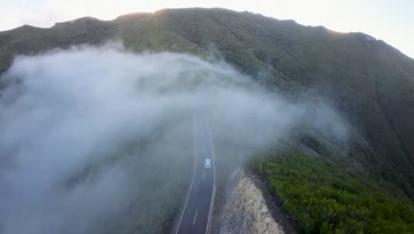 Coche-Conduciendo-Por-Una-Carretera-De-Montaña-Rodeada-De-Bosque-Dentro-De-Una-Nube