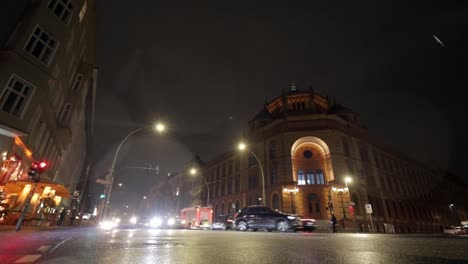 Oranienburger-Strasse-and-Tucholskystr-intersection-with-busy-traffic-moving-in-a-winter-night-with-light-snowfall