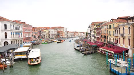 Panning-shot-over-Grand-Canal-with-people-debarking-from-Vaporetto,-Venice