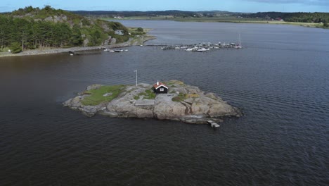 Small-cabin-on-rocky-island-surrounded-by-water-on-the-Swedish-west-coast-during-mid-day-in-summer