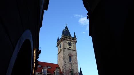 View-from-dark-alley-to-Old-Town-city-hall-clock-tower-exterior,-Prague