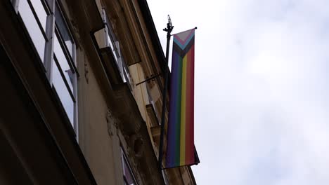 Outdoor-pole-banner-with-LGBTQ-rainbow-flag-near-apartment-building-facade