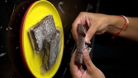Slow-motion-vertical-close-up-of-a-pair-of-woman's-hands-slicing-braking-a-brownie-in-half-at-a-restaurant
