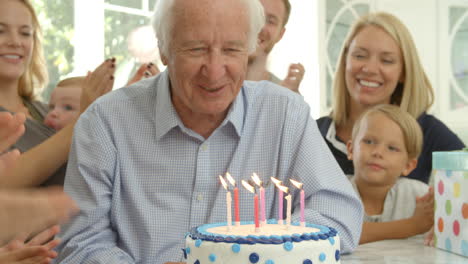 Grandfather-Blows-Out-Candles-On-Birthday-Cake-Shot,-Slow-Motion