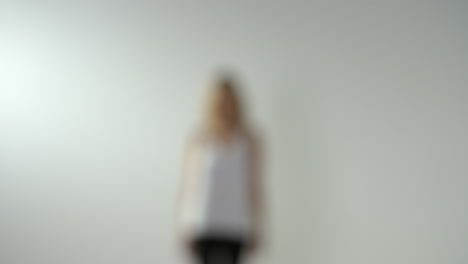 Young-blonde-woman-walks-to-camera,-into-focus,-slow-motion