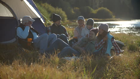 Multi-generation-family-relaxing-outside-tent-in-countryside