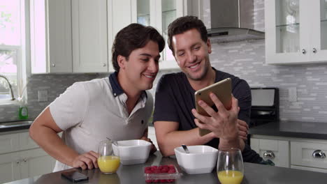 Tilt-shot-of-male-couple-using-tablet-computer-at-breakfast,-shot-on-R3D