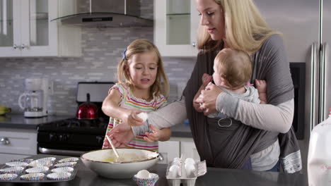 Young-girl-preparing-cake-mix-mix-in-kitchen,-mum-showing-baby,-shot-on-R3D