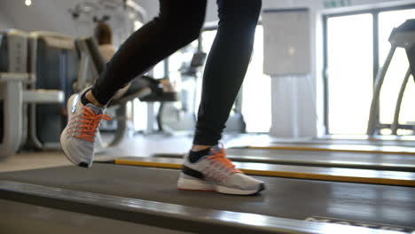 Woman-exercising-on-running-machine-at-a-gym,-low-section