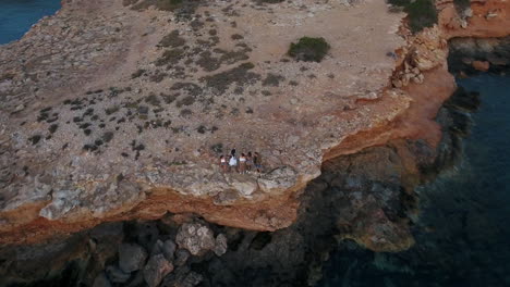 Aerial-Shot-Of-Friends-On-Cliffs-Watching-Sun-Set-Over-Sea