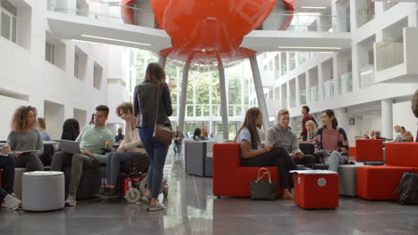 Students-socialising-in-the-lobby-of-a-university,-low-angle