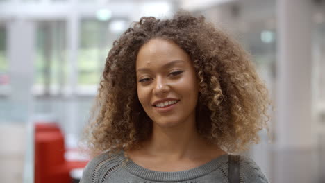 Smiling-female-university-student-walking-into-focus-indoors