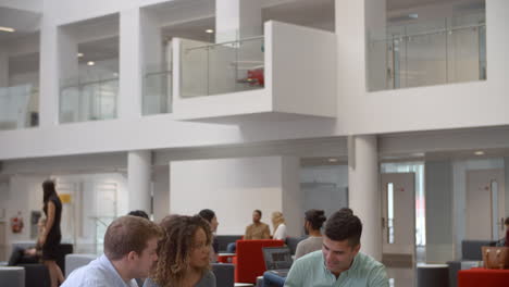 Students-studying-together-in-a-university-atrium,-tilt-shot