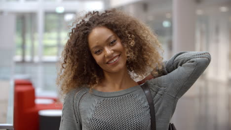 Smiling-female-university-student-walking-into-focus-indoors