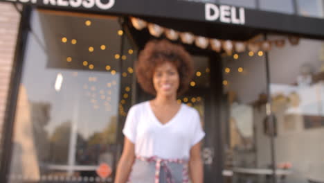 Black-female-owner-walks-into-focal-plane-in-front-of-cafe