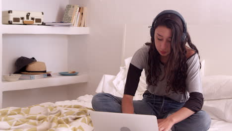 Teenager-Mädchen-Sitzt-Mit-Kopfhörern-Auf-Dem-Bett-Und-Benutzt-Laptop,-Aufgenommen-Auf-R3D