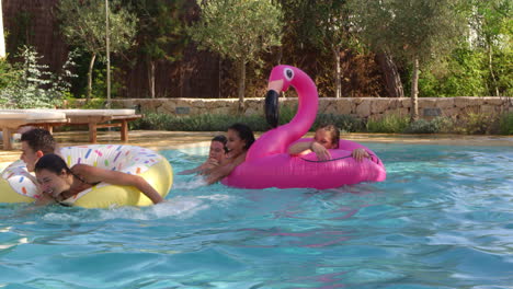 Teenage-friends-have-fun-with-inflatables-in-a-swimming-pool,-shot-on-R3D