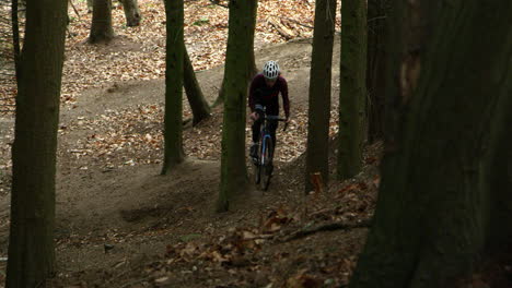 Man-climbs-forest-slope-on-cross-country-cycle,-front-view,-shot-on-R3D