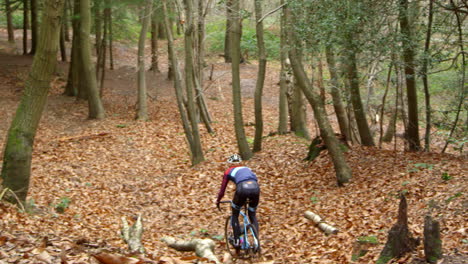 Young-man-cross-country-cycling-through-a-forest,-shot-on-R3D
