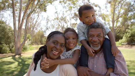 Mixed-race-grandparents-piggyback-with-grandchildren-in-park