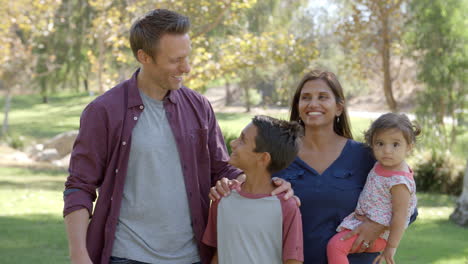 Happy-mixed-race-family-walking-into-focus-together-in-park