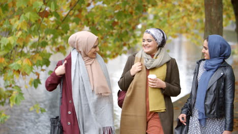 British-Muslim-Female-Friends-Walking-By-River-In-City