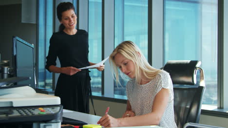 Zwei-Geschäftsfrauen,-Die-Am-Schreibtisch-Arbeiten,-Besprechen-Dokument