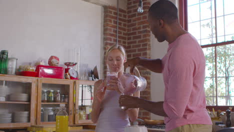 Mixed-race-couple-pouring-homemade-smoothies-in-kitchen,-shot-on-R3D