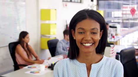 Young-black-woman-in-office-walks-into-focus-and-smiles