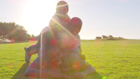Happy-black-family-lying-in-a-pile-on-grass-outdoors