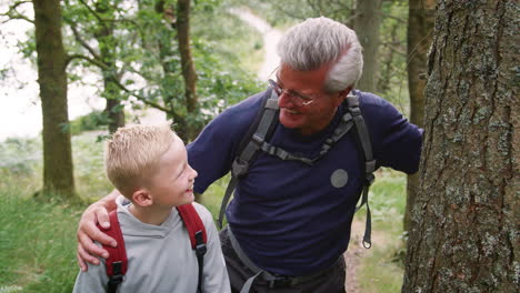 Grandfather-and-grandson-taking-a-break-while-hiking-in-a-forest,-Lake-District,-UK