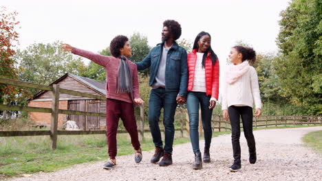 Mixed-race-family-walking-together-along-a-path-in-the-countryside,-low-angle