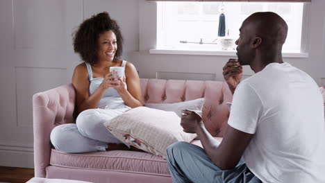 Young-mixed-race-couple-relax-together,-drinking-coffee-and-talking-in-their-living-room,-close-up