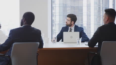 Reifer-Geschäftsmann-Hält-Im-Modernen-Büro-Eine-Präsentation-Vor-Kollegen,-Die-Am-Tisch-Sitzen