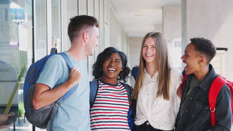 Gruppe-Lächelnder-Männlicher-Und-Weiblicher-College-Studenten,-Die-Durch-Den-Korridor-Des-Schulgebäudes-Gehen