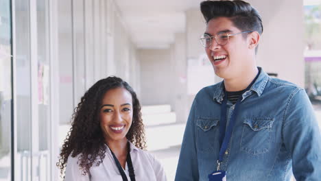 Portrait-Of-Smiling-Male-And-Female-School-Teachers-Standing-In-Corridor-Of-College-Building