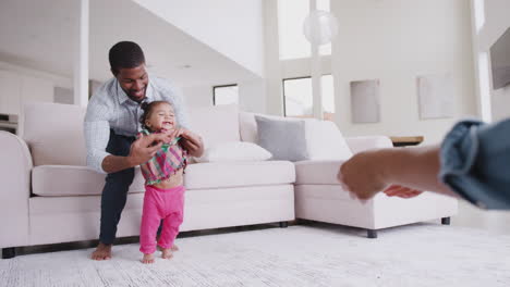 Parents-At-Home-Encouraging-Baby-Daughter-To-Take-First-Steps