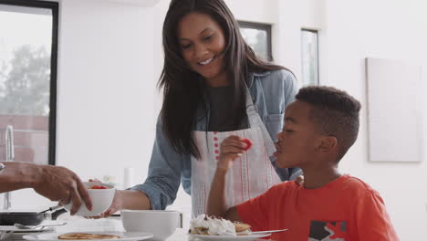 Eltern-In-Der-Küche-Mit-Sohn,-Der-Gemeinsam-Pfannkuchen-Und-Erdbeeren-Isst