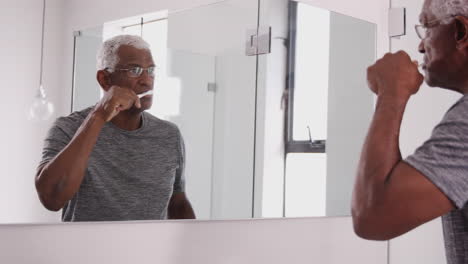 Älterer-Mann-Im-Schlafanzug-Blickt-Auf-Das-Spiegelbild-Im-Badezimmerspiegel-Und-Putzt-Zähne