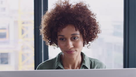 Young-black-female-creative-looking-at-computer-monitor-in-an-office-and-drinking-coffee,-close-up