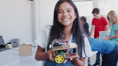 Portrait-Of-Female-Student-Holding-Robot-Vehicle-In-After-School-Computer-Coding-Class