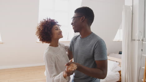 Young-Couple-Having-Fun-In-New-Home-Dancing-Together