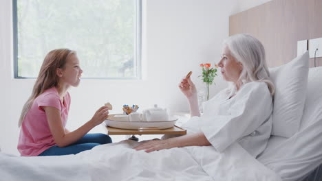 Granddaughter-Visiting-Grandmother-In-Hospital-Bed-For-Afternoon-Tea